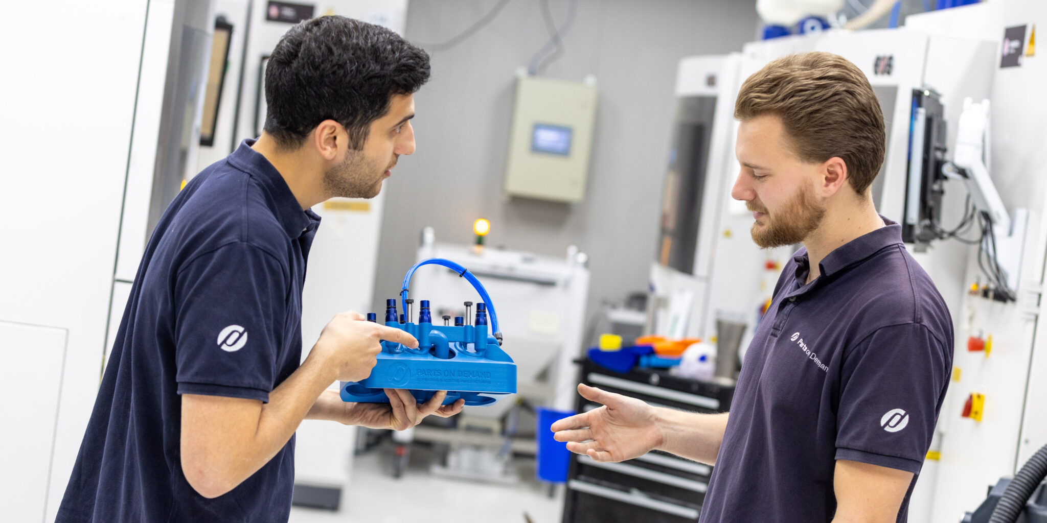 Twee engineers bij Parts on Demand bespreken een SLS-onderdeel naast de EOS P500